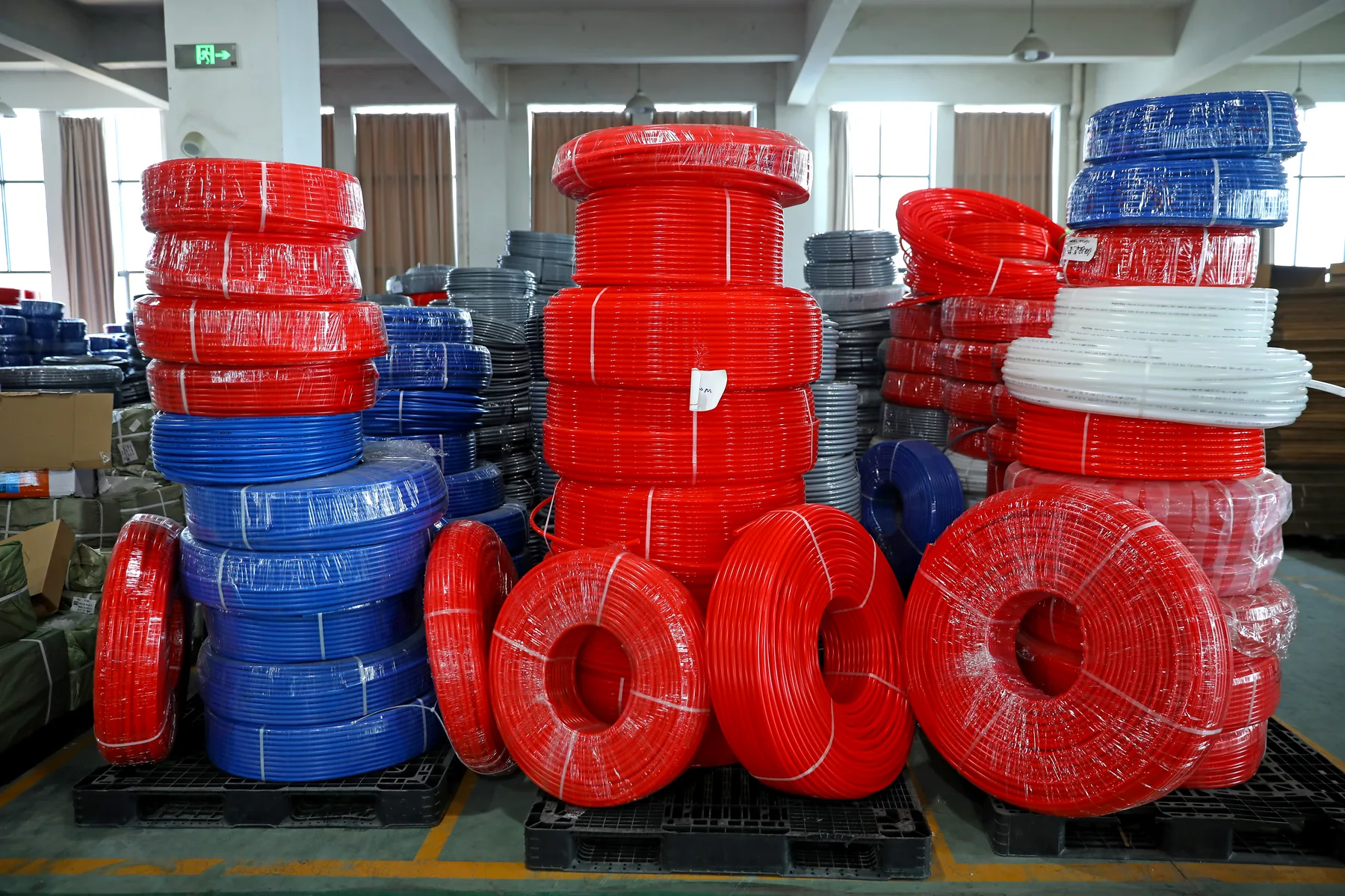 Coils of oxygen barrier PEX pipe for underfloor heating stacked in a manufacturer warehouse